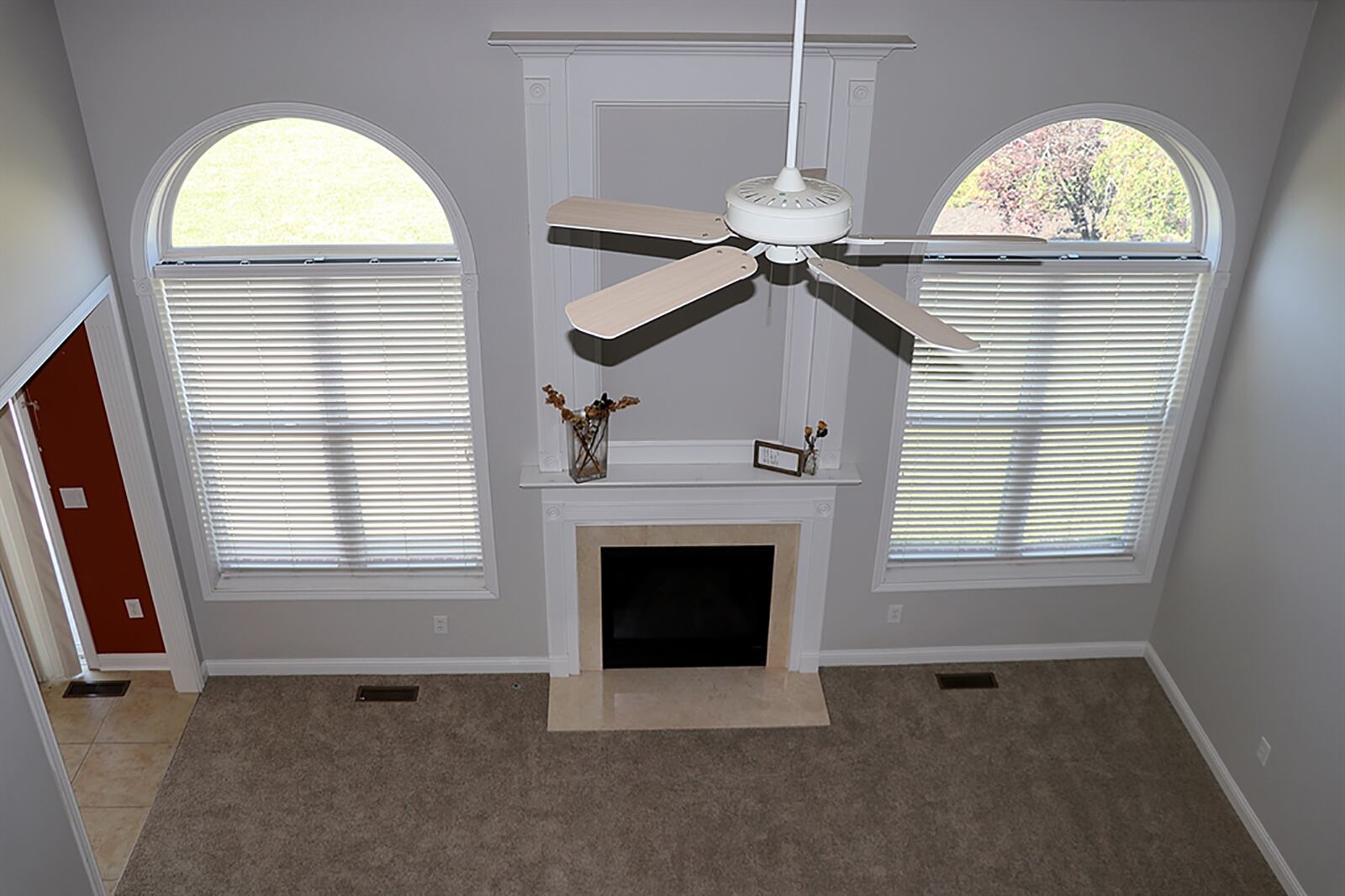 A vaulted ceiling peaks up to the second-floor catwalk above the great room. A gas fireplace with a double wood mantel and ceramic hearth is flanked by large arched windows. The neutral carpeting within the great room has been updated. CONTRIBUTED PHOTO BY KATHY TYLER