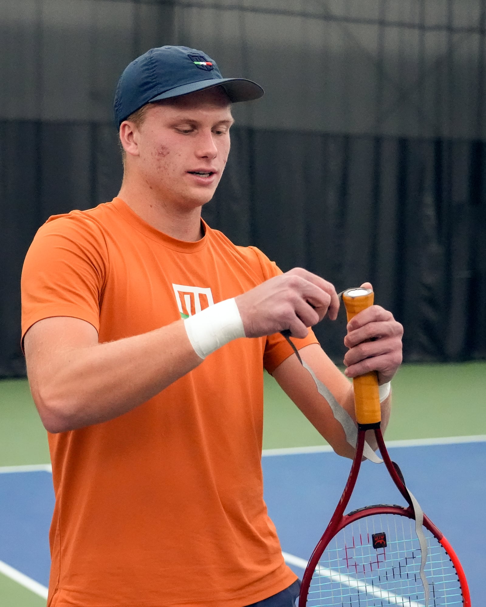 Tennis player Jenson Brooksby fixes tape on his racket grip during a practice session on the indoor courts at the USTA national campus Tuesday, Dec. 10, 2024, in Orlando, Fla. (AP Photo/John Raoux)