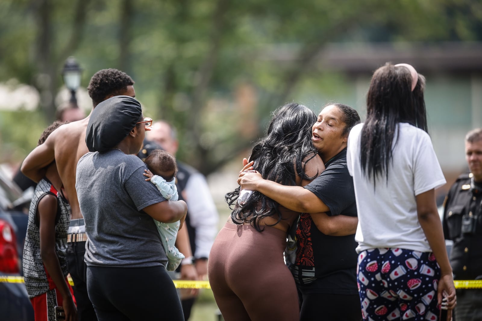 People embrace outside a home after a person was reported shot Friday afternoon, Aug. 6, 2021, inside the home in the 4900 block of Ericson Avenue in Jefferson Twp. JIM NOELKER/STAFF