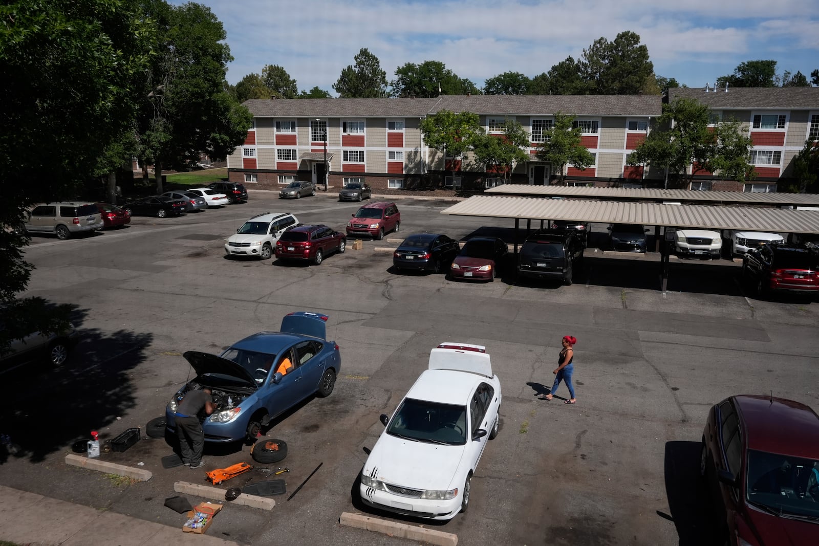 Gabriela Ramírez, right, walks over to her two friends who were trying to repair a mechanical issue with her car Thursday, Aug. 29, 2024, in Aurora, Colo. (AP Photo/Godofredo A. Vásquez)