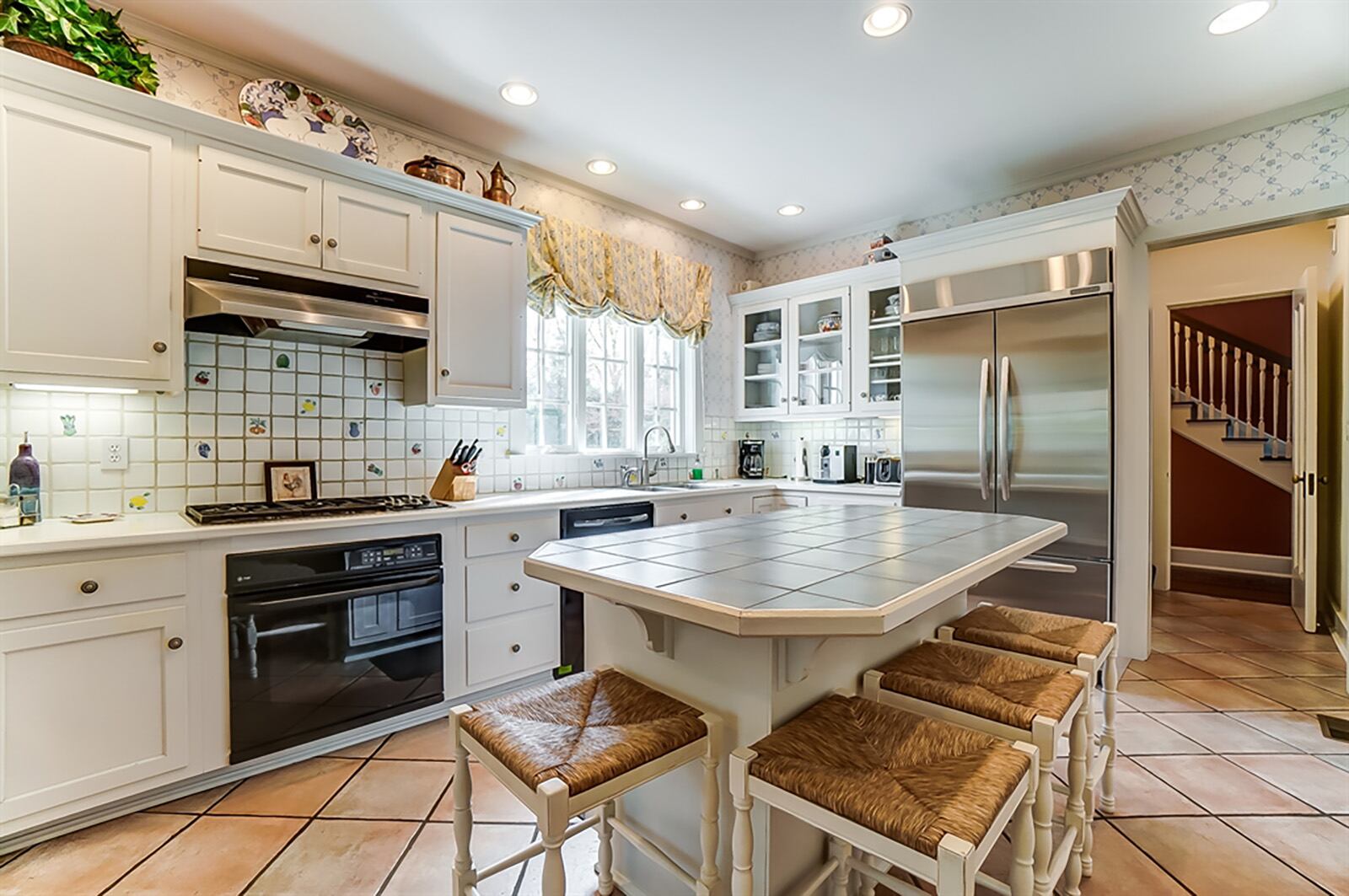 Continuing from the butler’s pantry, the kitchen has matching white cabinetry with glass-front cabinets that surround the appliances, including a Wolf five-burner gas cooktop, dishwasher, oven and microwave. A double sink is below triple windows. CONTRIBUTED PHOTO