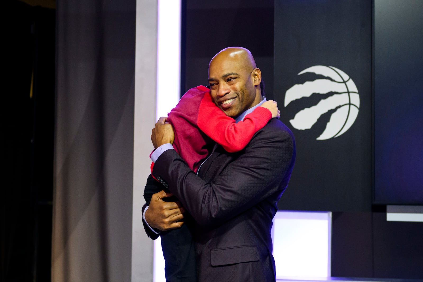 Former Toronto Raptors player Vince Carter hugs his son, Vince Carter Jr., after speaking to media ahead of his number retirement, before an NBA basketball game between the Toronto Raptors and the Sacramento Kings at the Scotiabank arena in Toronto on Saturday, Nov. 2, 2024. (Christopher Katsarov/The Canadian Press via AP)