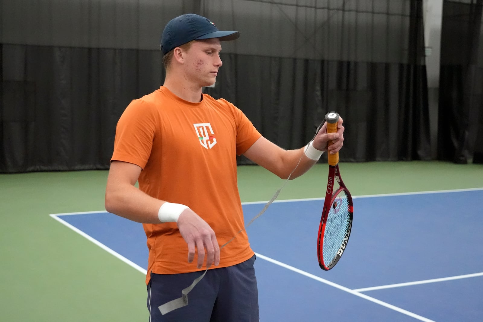 Tennis player Jenson Brooksby fixes tape on his racket grip during a practice session on the indoor courts at the USTA national campus Tuesday, Dec. 10, 2024, in Orlando, Fla. (AP Photo/John Raoux)