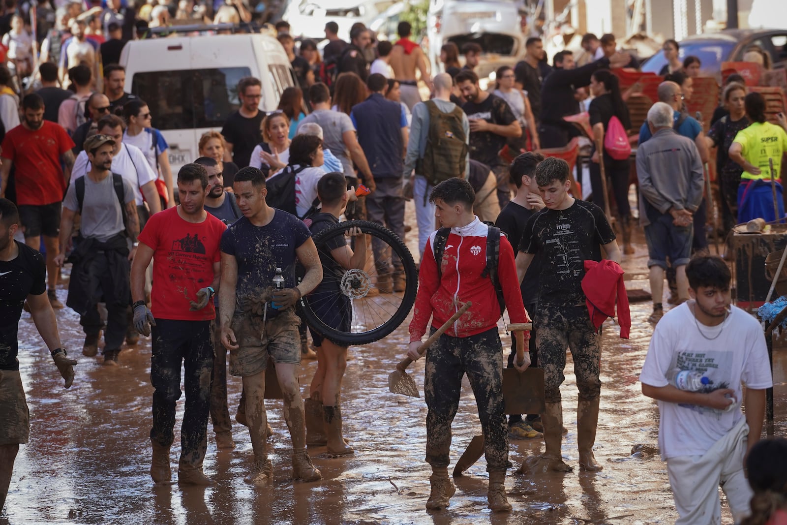 People walks through the mud at an area affected by floods in Paiporta, near Valencia, Spain, Friday, Nov. 1, 2024. (AP Photo/Alberto Saiz)