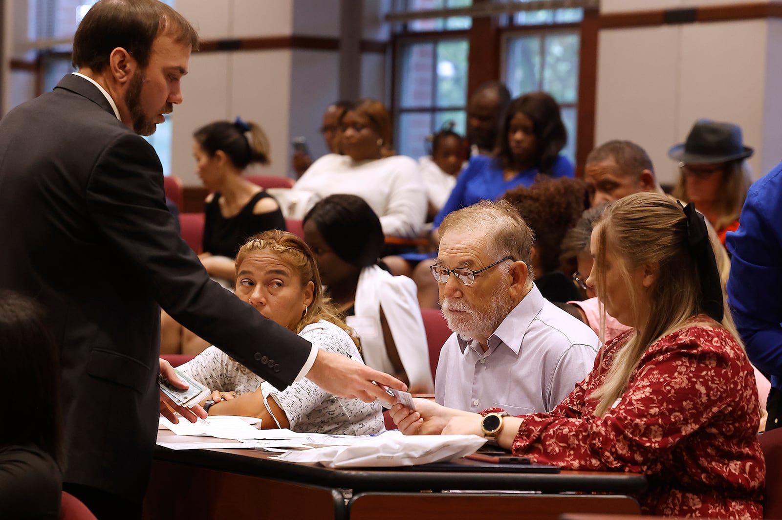 Levi Fisher of U.S. Citizenship and Immigration Services collects the green cards before the immigrants are sworn in as American citizens at the naturalization ceremony held at the University of Dayton School of Law on Sept. 18, 2023. BILL LACKEY/STAFF