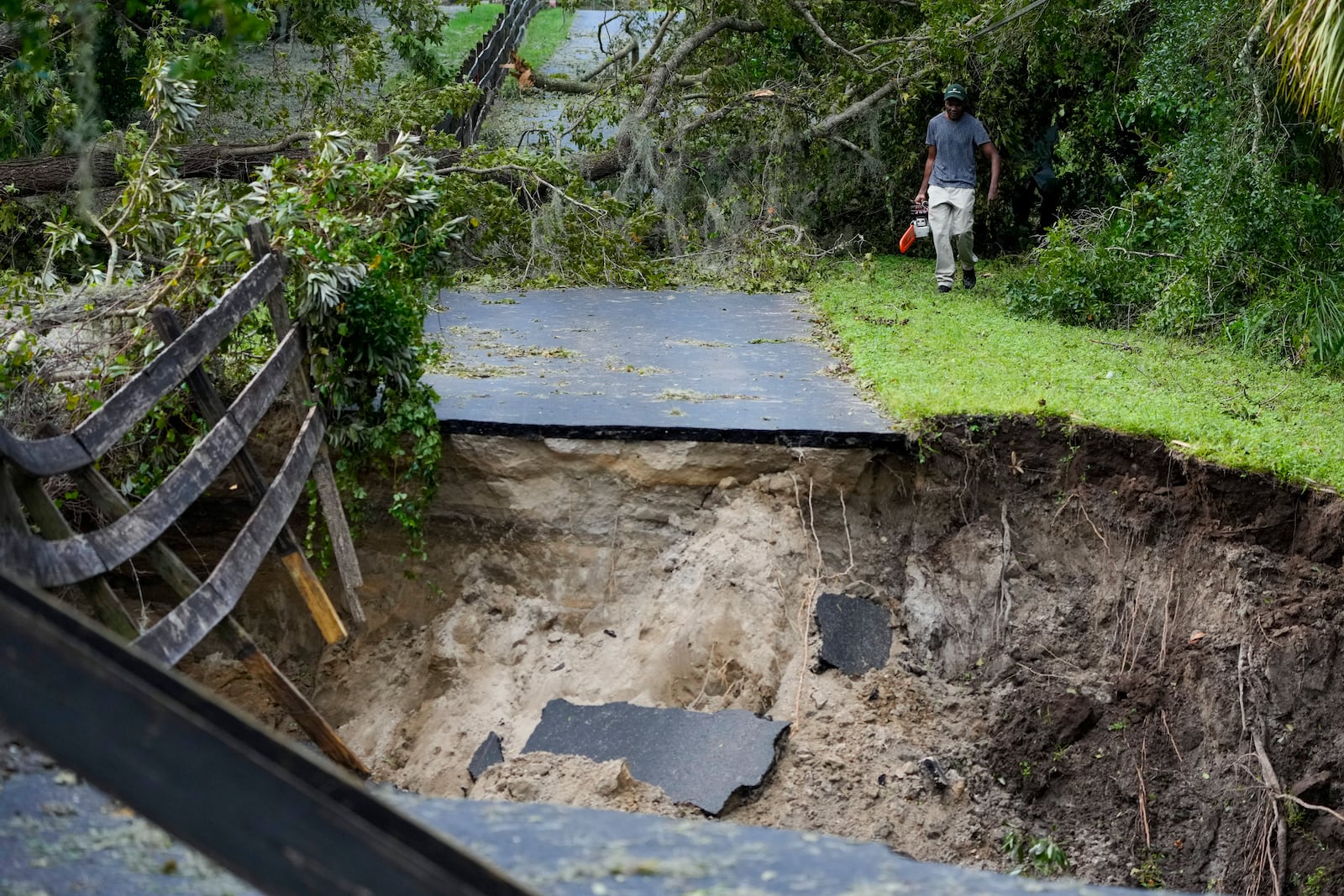 Renel Prophet carries a chainsaw to get it repaired after it broke while cleaning out down trees in his property, which became unaccessible during Hurricane Milton, Friday, Oct. 11, 2024, in Riverview, Fla. (AP Photo/Julio Cortez)