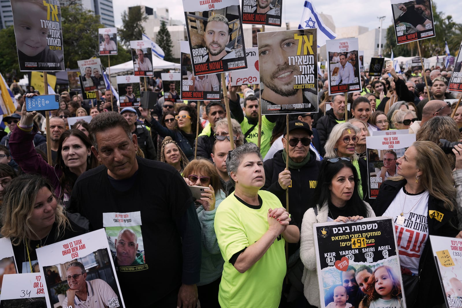 People holding posters with photos of Israelis hostages Eli Sharabi, Or Levy and Ohad Ben Ami, gather at the so-called "hostages square" waiting for their release in Tel Aviv, Israel on Saturday, Feb. 8, 2025. (AP Photo/Oded Balilty)