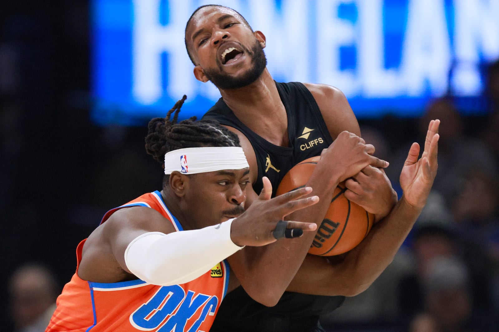 Oklahoma City Thunder guard Luguentz Dort, left, tries to steal the ball from Cleveland Cavaliers forward Evan Mobley, right, during the first half of an NBA basketball game, Thursday, Jan. 16, 2025, in Oklahoma City. (AP Photo/Nate Billings)