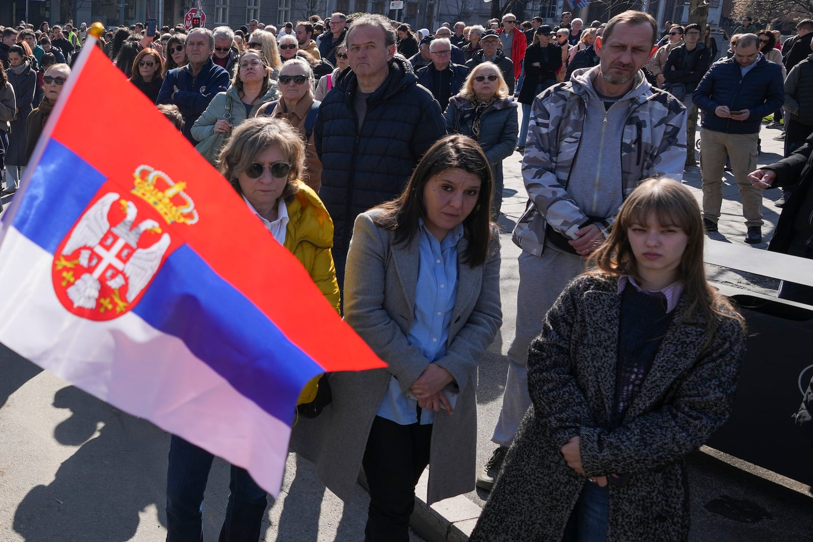 People stand in silence to commemorate the 15 victims killed after a railway concrete canopy fell in November 2024, during a Serbia's parliament session in Belgrade, Serbia, Tuesday, March 4, 2025. (AP Photo/Darko Vojinovic)