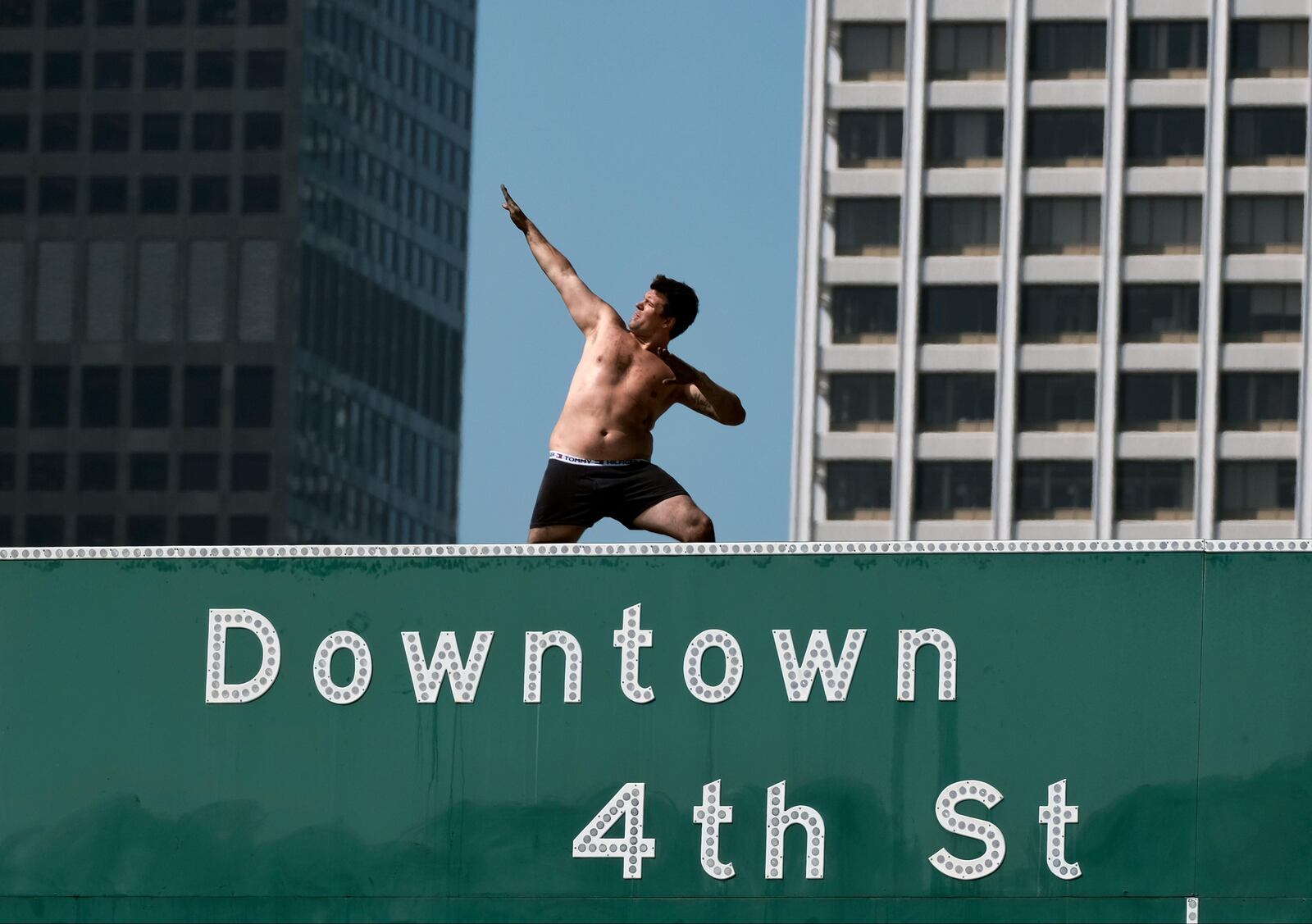 An activist poses atop a freeway sign while California Highway Patrol officers try to coax the man down in downtown Los Angeles on Wednesday, June 27, 2018. The man suspended banners, one about fighting pollution, after climbing onto the sign over State Route 110 during the Wednesday morning rush hour.