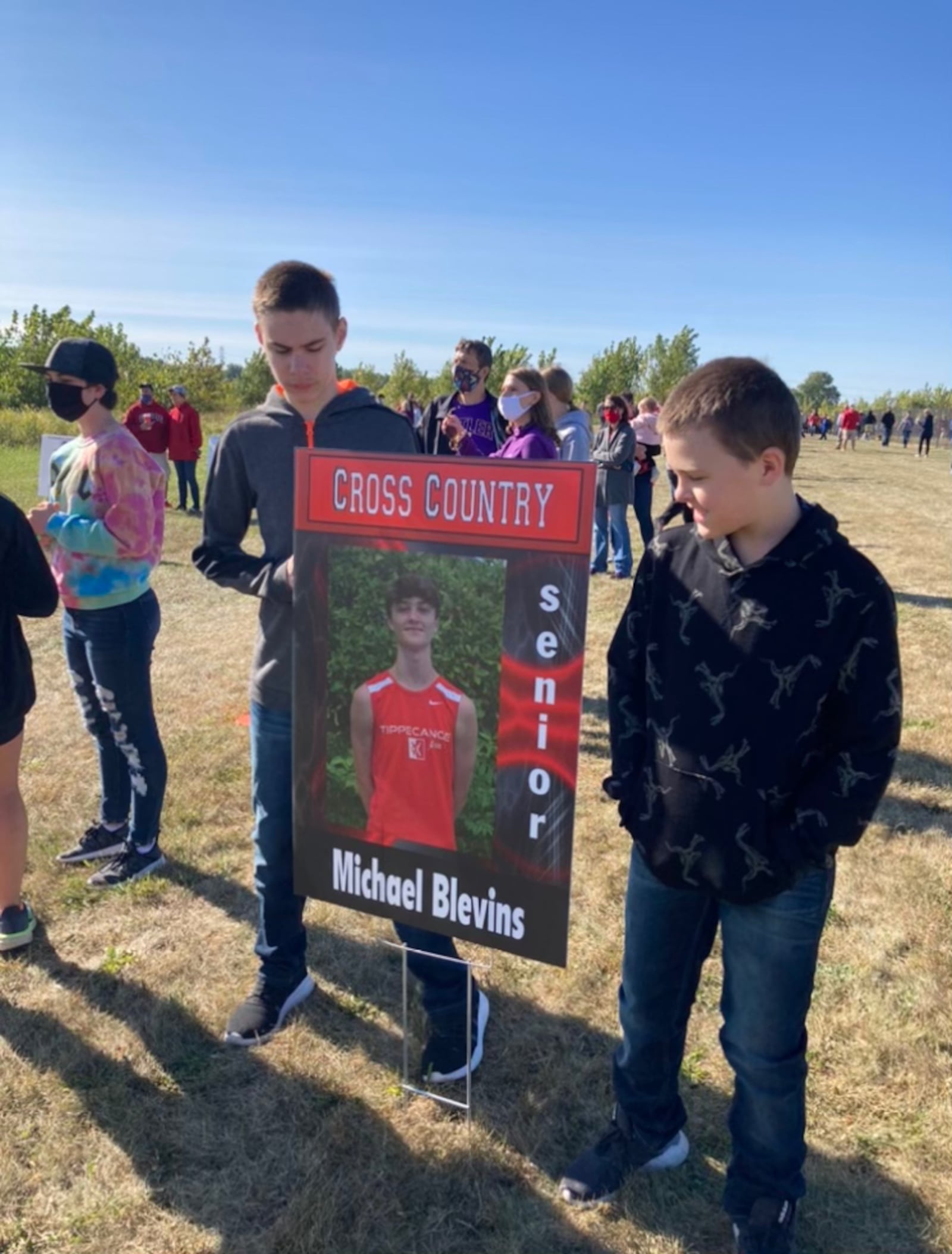 Logan Edens, left, of the Troy Junior High School cross country team, poses for a photo with a poster of his cousin. Photo courtesy of Liz Edens