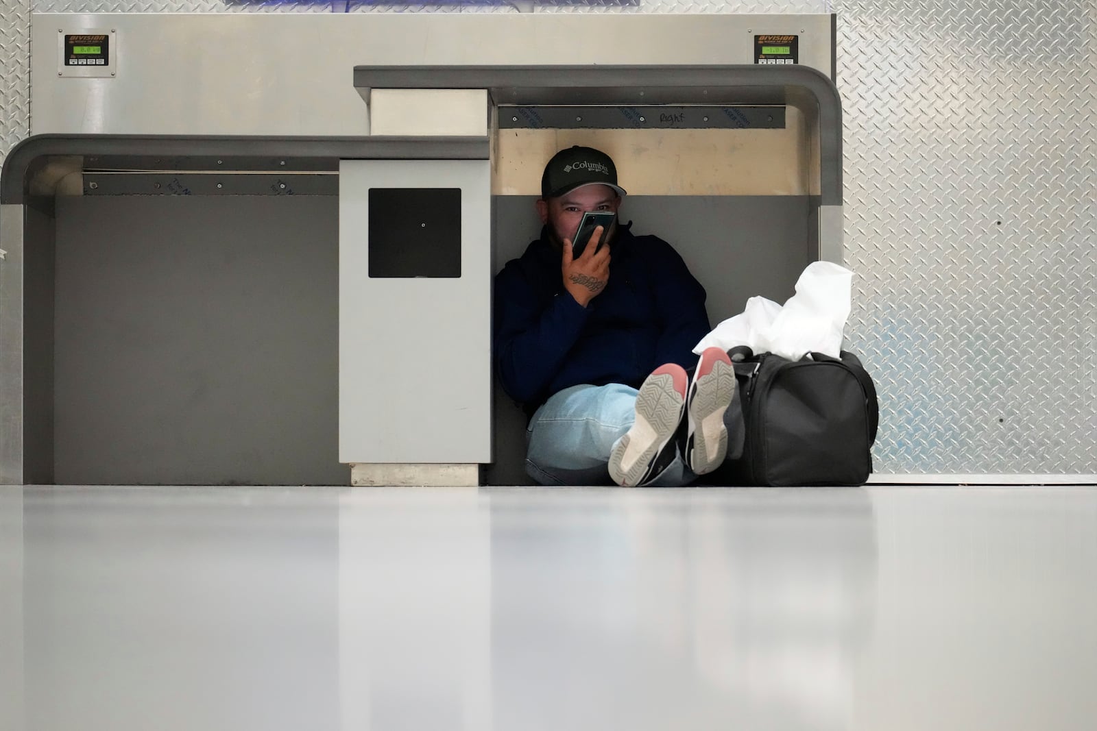 Alvaro Perez, who spent a night at the closed George Bush Intercontinental Airport, waits for the next flight out Tuesday, Jan. 21, 2025, in Houston. (AP Photo/David J. Phillip)