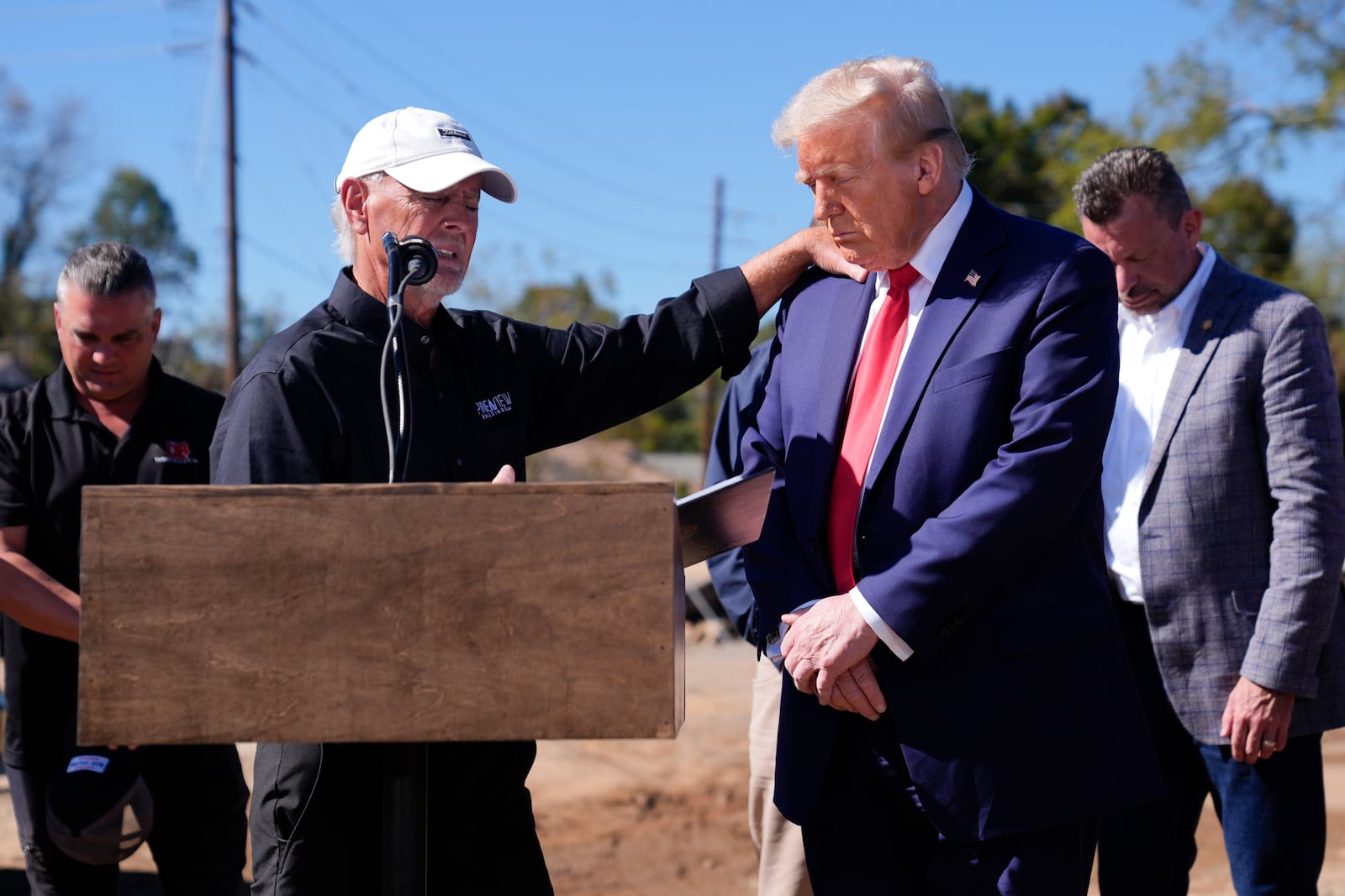 Republican presidential nominee former President Donald Trump prays with others after delivering remarks on the damage and federal response to Hurricane Helene, Monday, Oct. 21, 2024, in Swannanoa, N.C. (AP Photo/Evan Vucci)