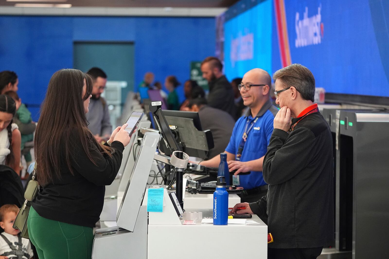 A traveler chats with agents at the Southwest Airlines check-in counter in Denver International Airport Tuesday, Nov. 26, 2024, in Denver. (AP Photo/David Zalubowski)