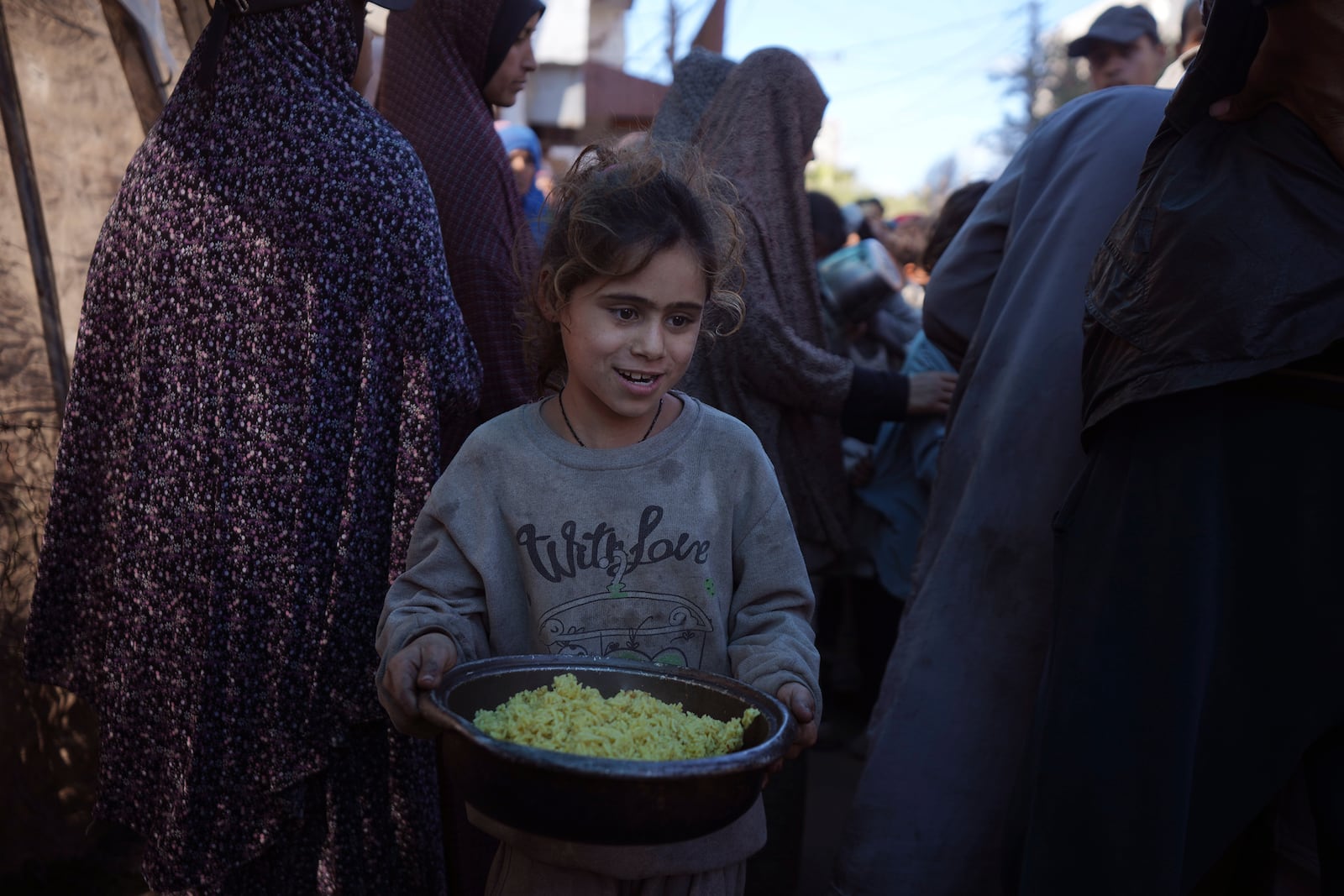 A Palestinian girl carries food that was distributed in Deir al-Balah, Gaza Strip, Friday, Dec. 13, 2024. (AP Photo/Abdel Kareem Hana)