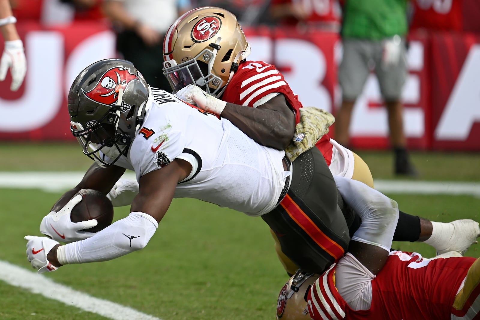 Tampa Bay Buccaneers running back Rachaad White (1) scores a touchdown against San Francisco 49ers safety Malik Mustapha, top, and linebacker De'Vondre Campbell during the second half of an NFL football game in Tampa, Fla., Sunday, Nov. 10, 2024. (AP Photo/Jason Behnken)