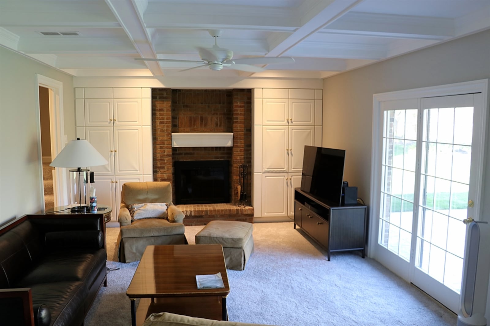 A step down from the breakfast room is the family room with a coffered ceiling and brick fireplace.