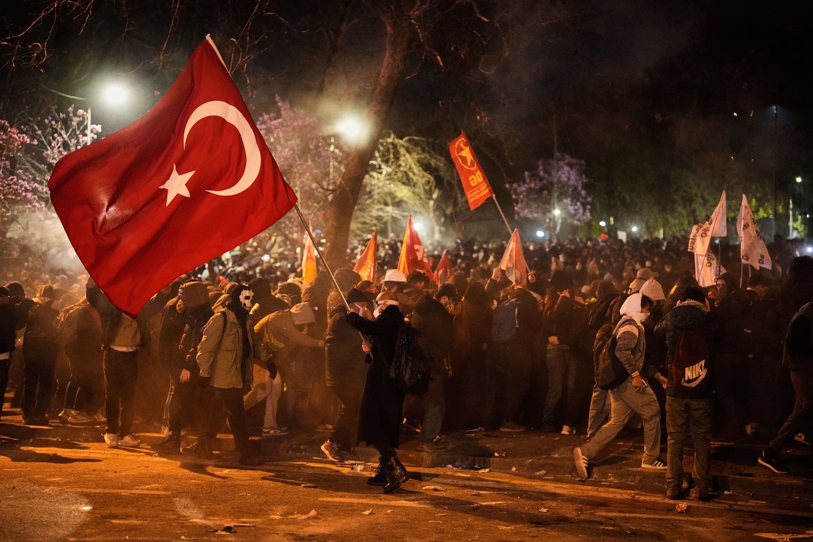 A man holds a Turkish flag as people clash with police during a protest against the arrest of Istanbul's Mayor Ekrem Imamoglu in Istanbul, Turkey, Friday, March 21, 2025. (AP Photo/Emrah Gurel)