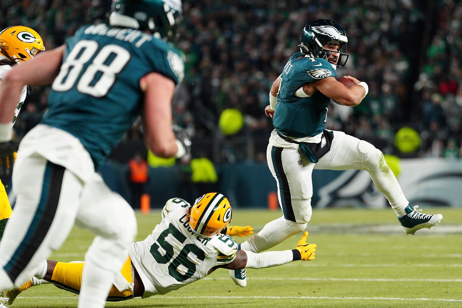 Philadelphia Eagles quarterback Jalen Hurts (1) breaks a tackle of Green Bay Packers linebacker Edgerrin Cooper (56) during the second half of an NFL wild-card playoff football game Sunday, Jan. 12, 2025, in Philadelphia. (AP Photo/Derik Hamilton)