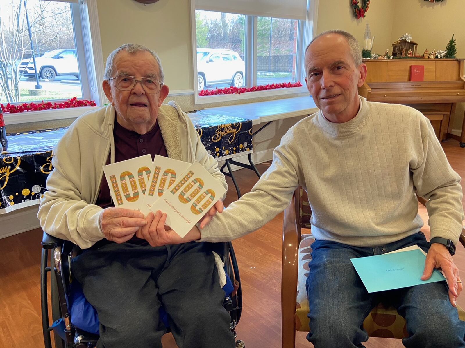 Elton Murphy (left), with son Chris, holds his 100th birthday signs. CONTRIBUTED