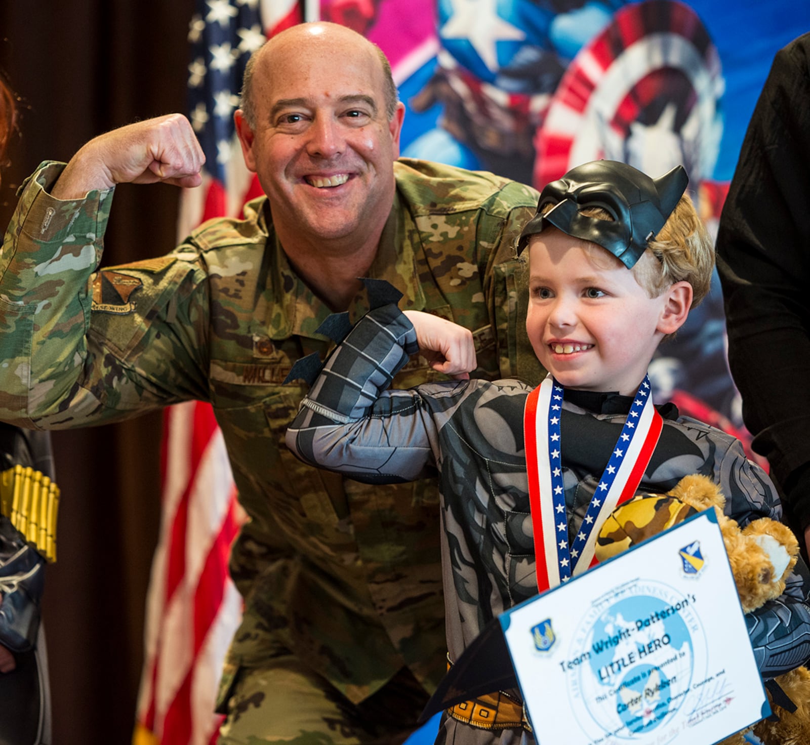 Col. Patrick Miller, 88th Air Base Wing and installation commander, flexes his muscles with a boy dressed as Batman during the “Little Heroes” celebration April 8 at Wright-Patterson Air Force Base. U.S. AIR FORCE PHOTO/JAIMA FOGG