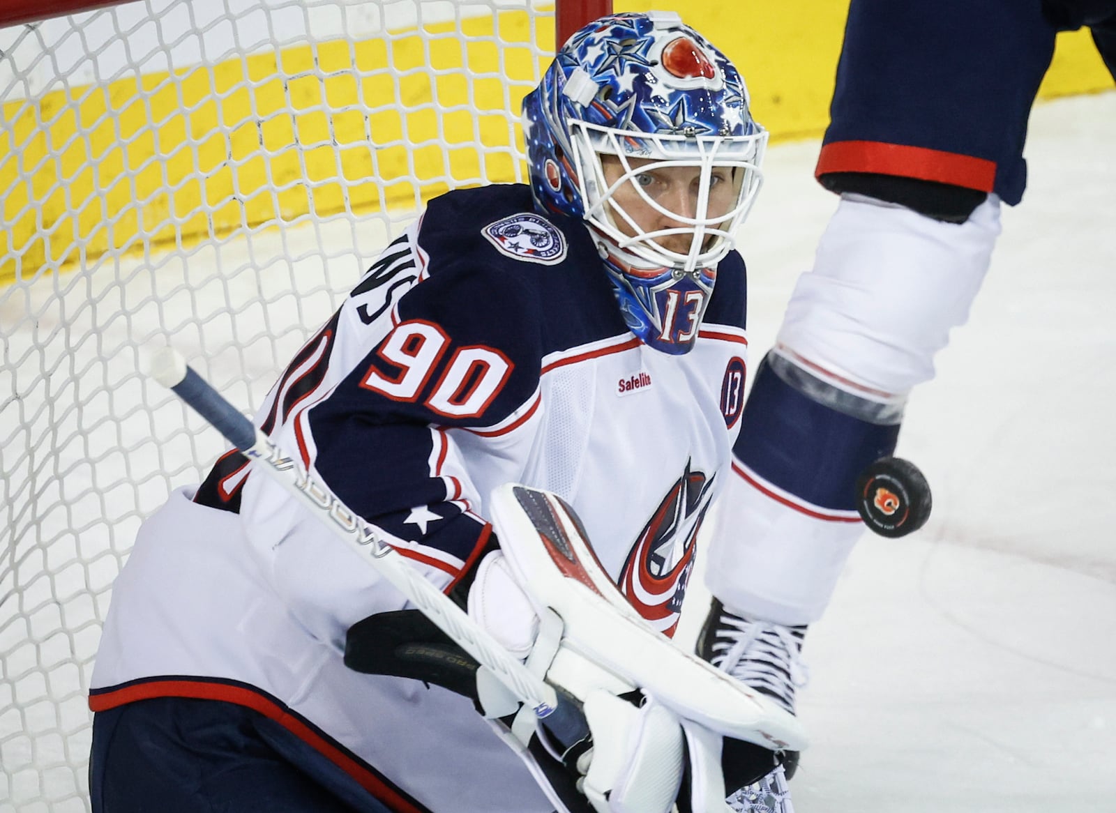 Columbus Blue Jackets goalie Elvis Merzlikins stops the puck during the first period of an NHL hockey gameagainst the Calgary Flames in Calgary, Tuesday, Dec. 3, 2024. (Jeff McIntosh/The Canadian Press via AP)