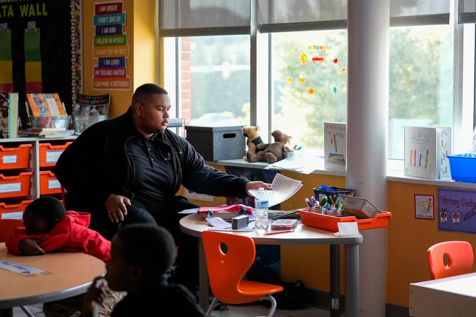 Leading Men fellow Davontez Johnson organizes a writing station during the classroom quiet time after preschoolers return from lunch, Thursday, Oct. 3, 2024, at Dorothy I. Height Elementary School in Baltimore. (AP Photo/Stephanie Scarbrough)