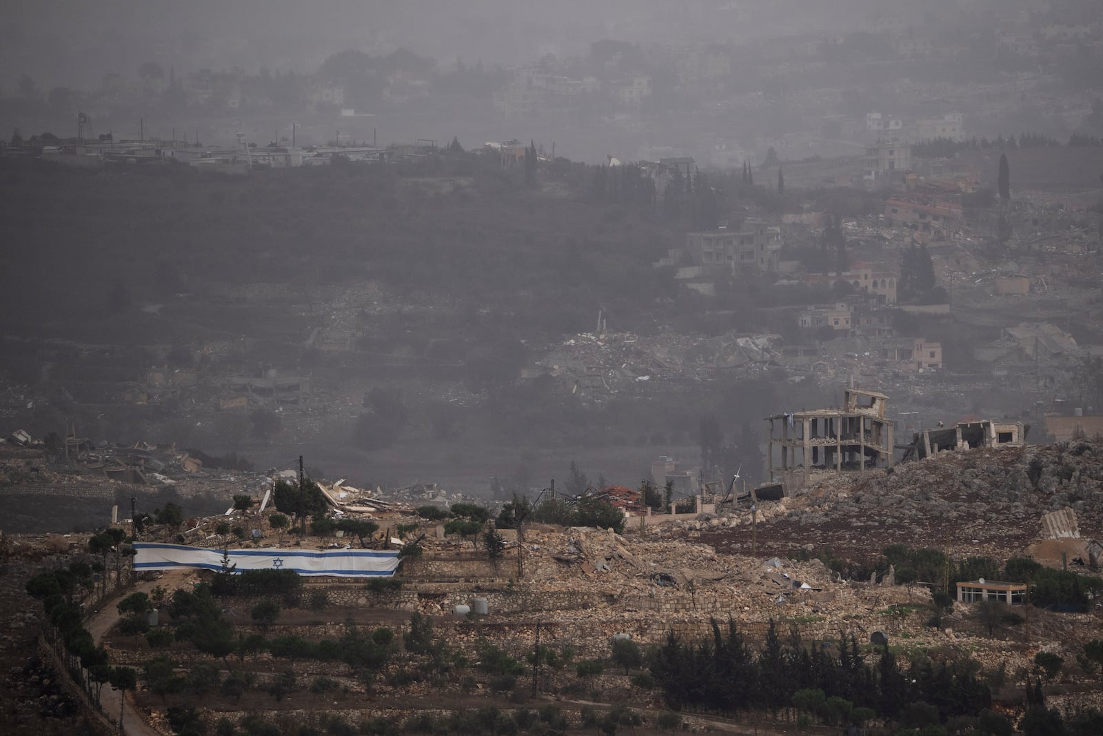 An Israeli flag stands next to destroyed buildings on an area in southern Lebanon as seen from northern Israel, Monday, Nov. 25, 2024. (AP Photo/Leo Correa)