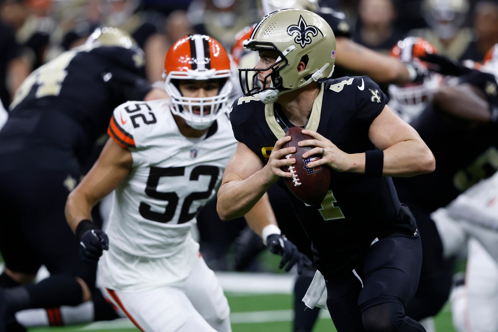 New Orleans Saints quarterback Derek Carr (4) rolls out in front of Cleveland Browns linebacker Elerson G. Smith (52) to pass to wide receiver Marquez Valdes-Scantling for a touchdown in the first half of an NFL football game in New Orleans, Sunday, Nov. 17, 2024. (AP Photo/Butch Dill)