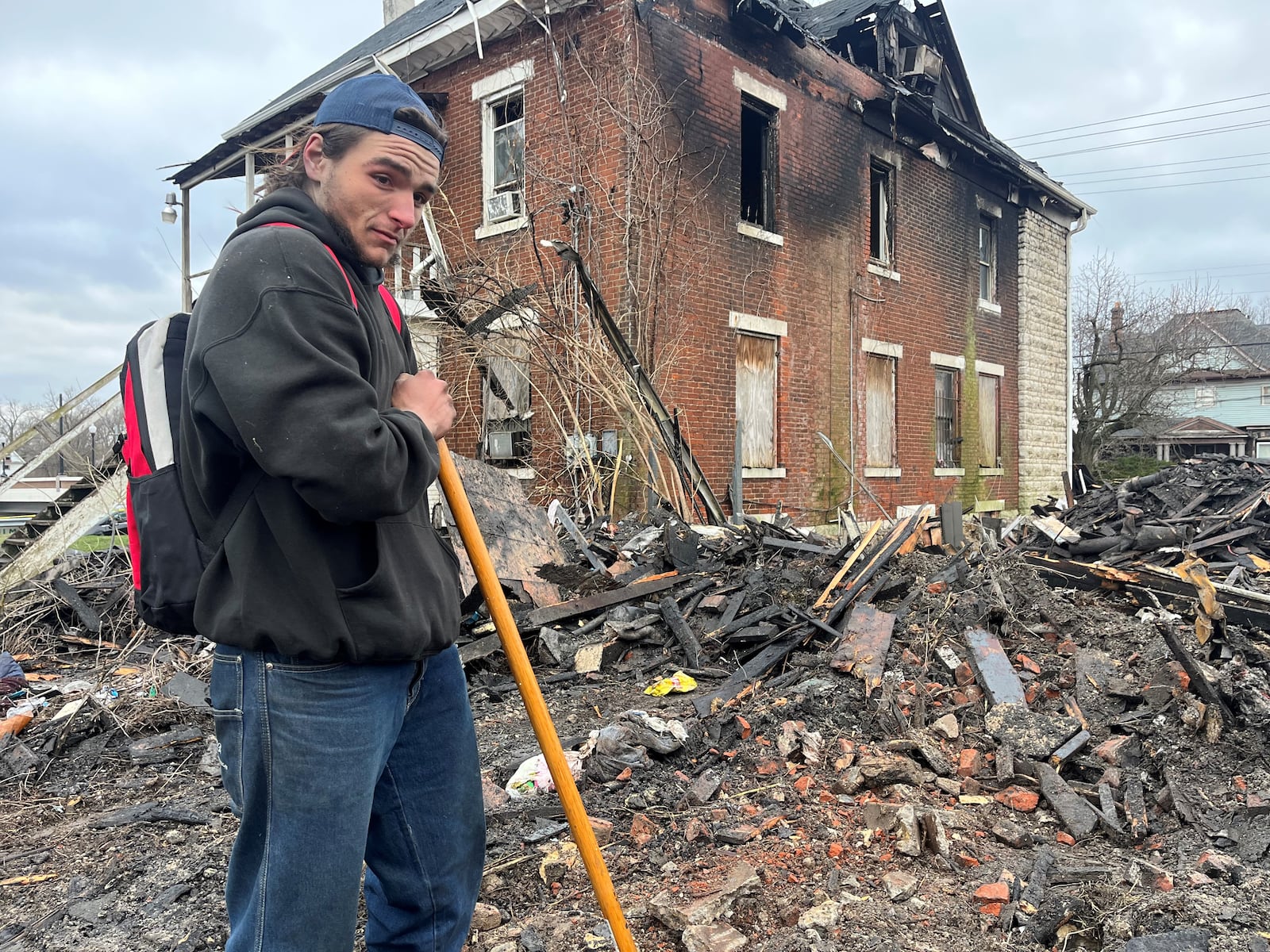 Jordan Trent, who was homeless, sifts through debris left over after a home on the 500 block of North Broadway Street burned down on March 8, 2023. Trent said he was in the home at the time of the fire. Five people were found dead at the property. CORNELIUS FROLIK / STAFF