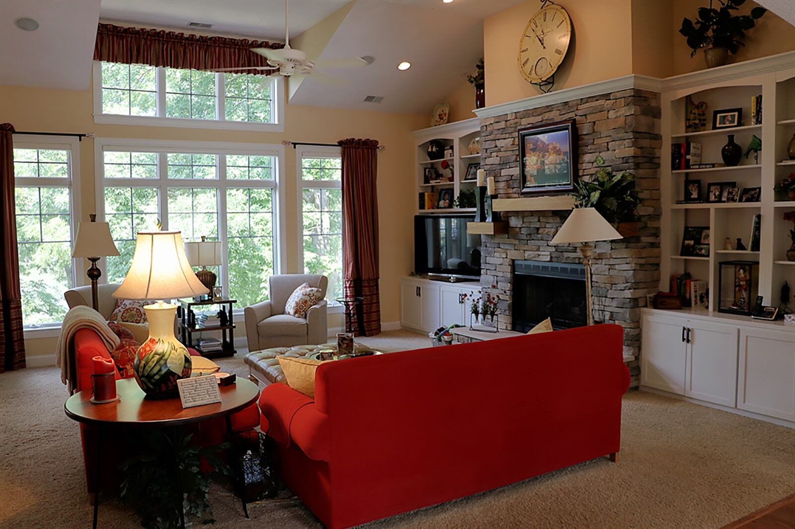 The foyer opens into a great room with a wall of windows overlooking the back yard and lake. A stack-stone, gas fireplace has three wood beam mantels and a raised stone hearth. Built-in white cabinetry offers open bookcases, cabinets and media display. CONTRIBUTED PHOTO BY KATHY TYLER