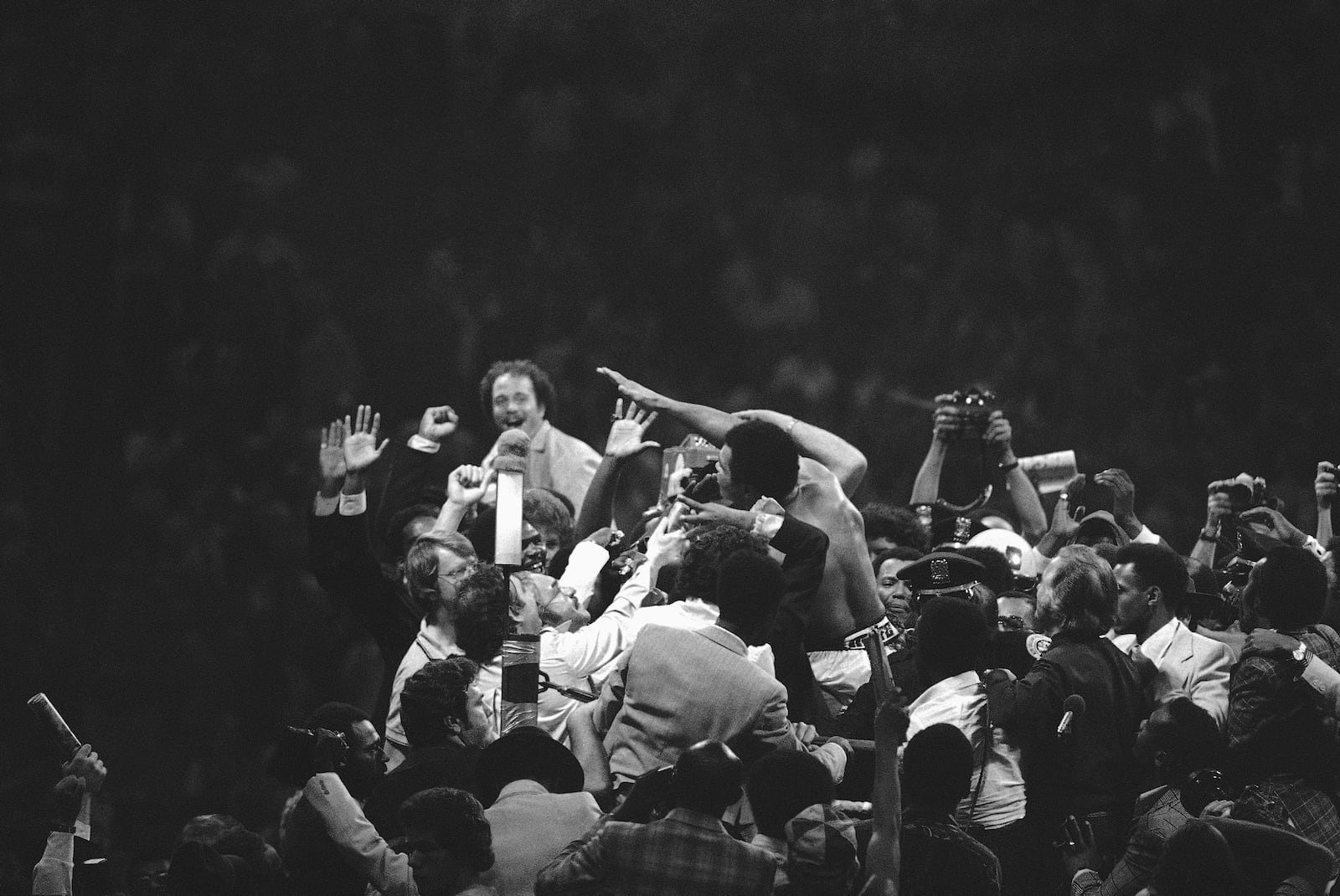 FILE - Muhammad Ali waves from the center of a crowded ring after he regained the heavyweight title with a 15-round unanimous decision over Leon Spinks at the Superdome in New Orleans, Sept. 15, 1978. (AP Photo, File)