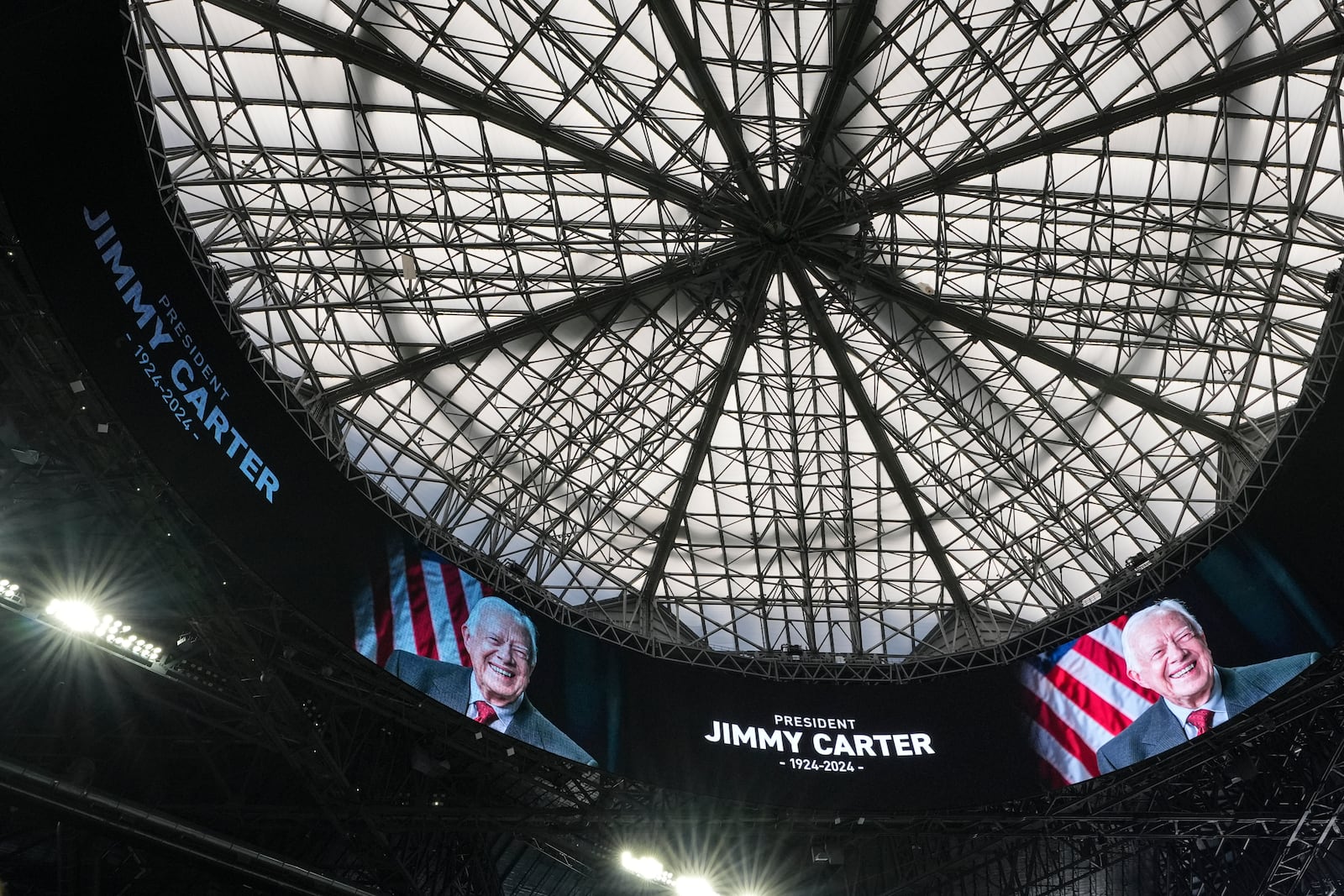 Monitors display an image of former President Jimmy Carter inside the Mercedes-Benz Stadium before the first half in the quarterfinals of a College Football Playoff between Texas and Arizona State, Wednesday, Jan. 1, 2025, in Atlanta. (AP Photo/Brynn Anderson)