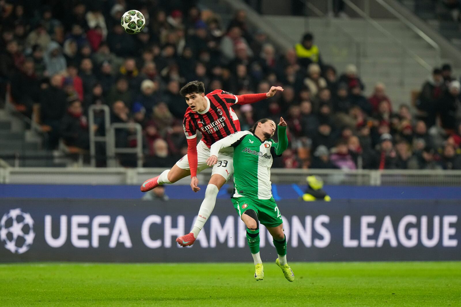 AC Milan's Davide Bartesaghi, left, jumps for a header with Feyenoord's Anis Hadj Moussa during Champions League, playoff second leg soccer match between AC Milan and Feyenoord, at the San Siro stadium in Milan, Italy, Tuesday, Feb.18, 2025. (AP Photo/Luca Bruno)