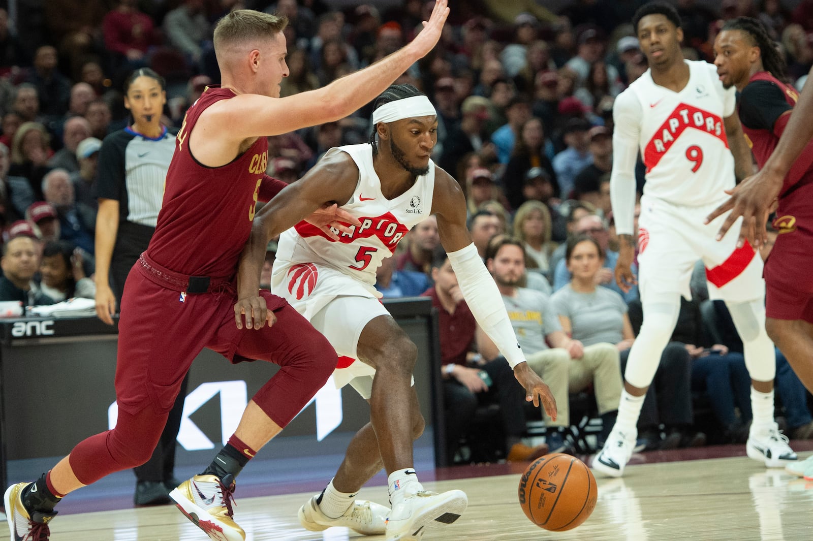 Toronto Raptors' Immanuel Quickley (5) drives past Cleveland Cavaliers' Sam Merrill, left, as RJ Barrett (9) and Darius Garland, right, watch during the first half of an NBA basketball game in Cleveland, Thursday, Jan. 9, 2025. (AP Photo/Phil Long)