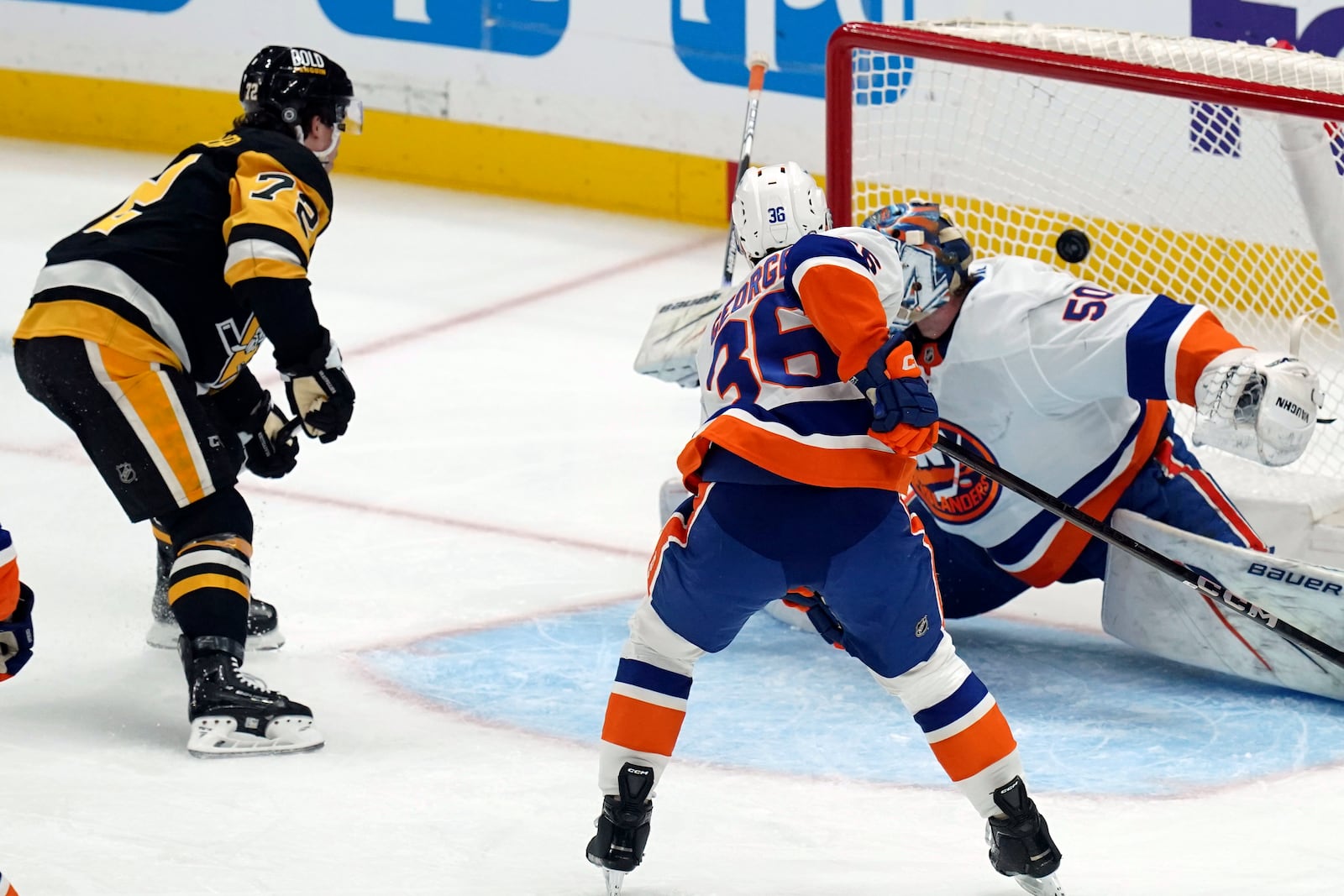 Pittsburgh Penguins' Anthony Beauvillier (72) scores against New York Islanders goaltender Marcus Hogberg (50) as Isaiah George (36) defends during the first period of an NHL hockey game, Sunday, Dec. 29, 2024, in Pittsburgh. (AP Photo/Matt Freed)