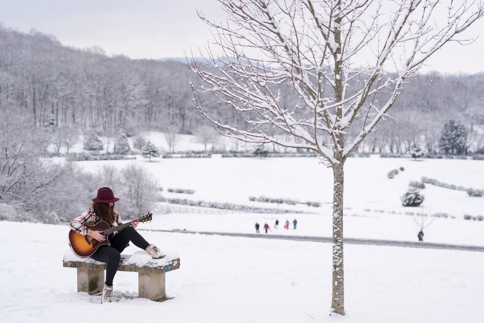 Victoria Collings plays a her guitar on a snow covered bench Saturday, Jan. 11, 2025, in Nashville, Tenn. (AP Photo/George Walker IV)