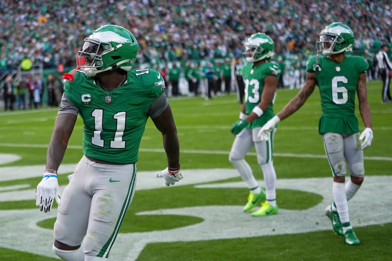 Philadelphia Eagles wide receiver A.J. Brown (11) launches the football onto the stands after catching a touchdown pass from quarterback Tanner McKee, not visible, during the second half of an NFL football game against the Dallas Cowboys, Sunday, Dec. 29, 2024, in Philadelphia. Looking on are wide receiver Jahan Dotson (83) and wide receiver DeVonta Smith (6). (AP Photo/Chris Szagola)