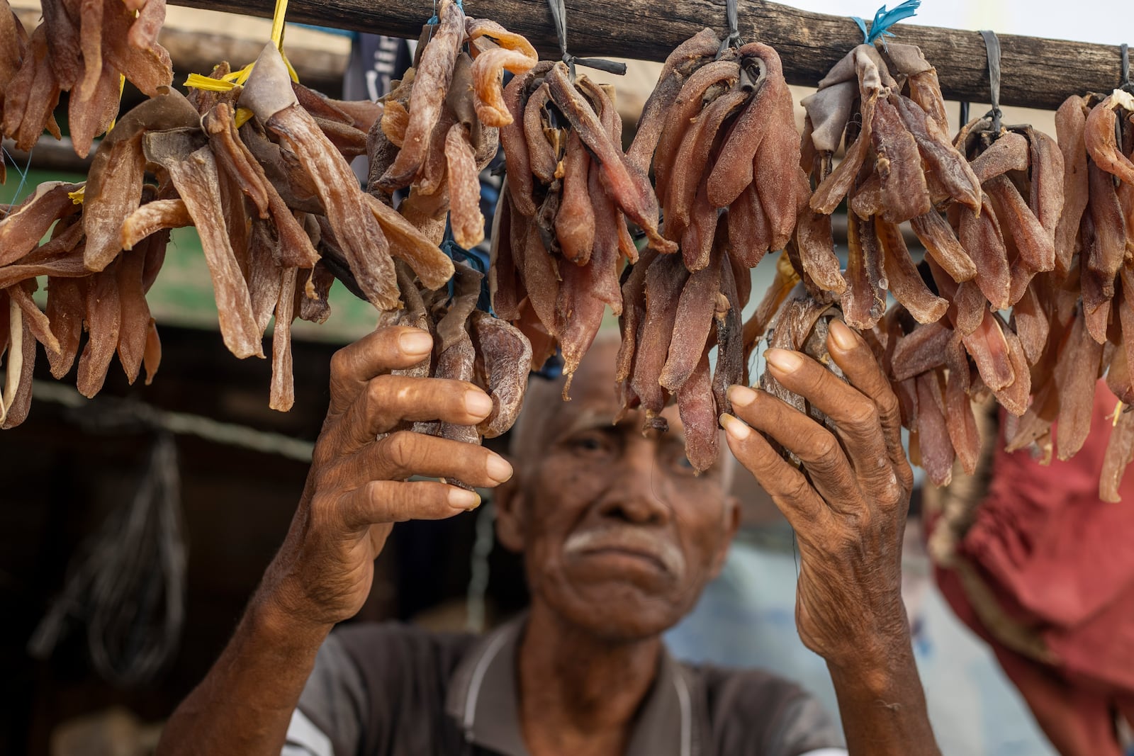 Ilyas, 70, who has been complaining of itchy skin rashes, checks on his dried fish at his house on Kabaena Island near nickel mining activities in South Sulawesi, Indonesia, Friday, Nov. 15, 2024. (AP Photo/Yusuf Wahil)