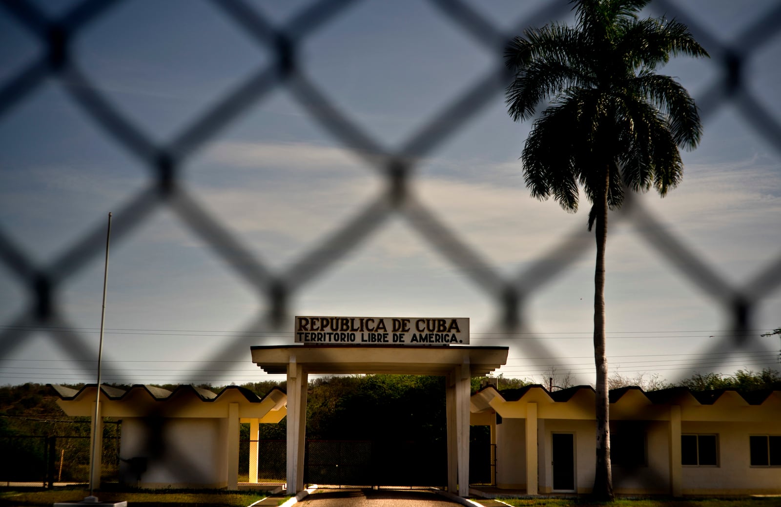 FILE - In this photo reviewed by U.S. military officials, a building in Cuba carries the Spanish message "Republic of Cuba. Free American Territory," behind a gate marking the border with the U.S. Guantanamo Bay naval base in Cuba, June 6, 2018. (AP Photo/Ramon Espinosa, File)