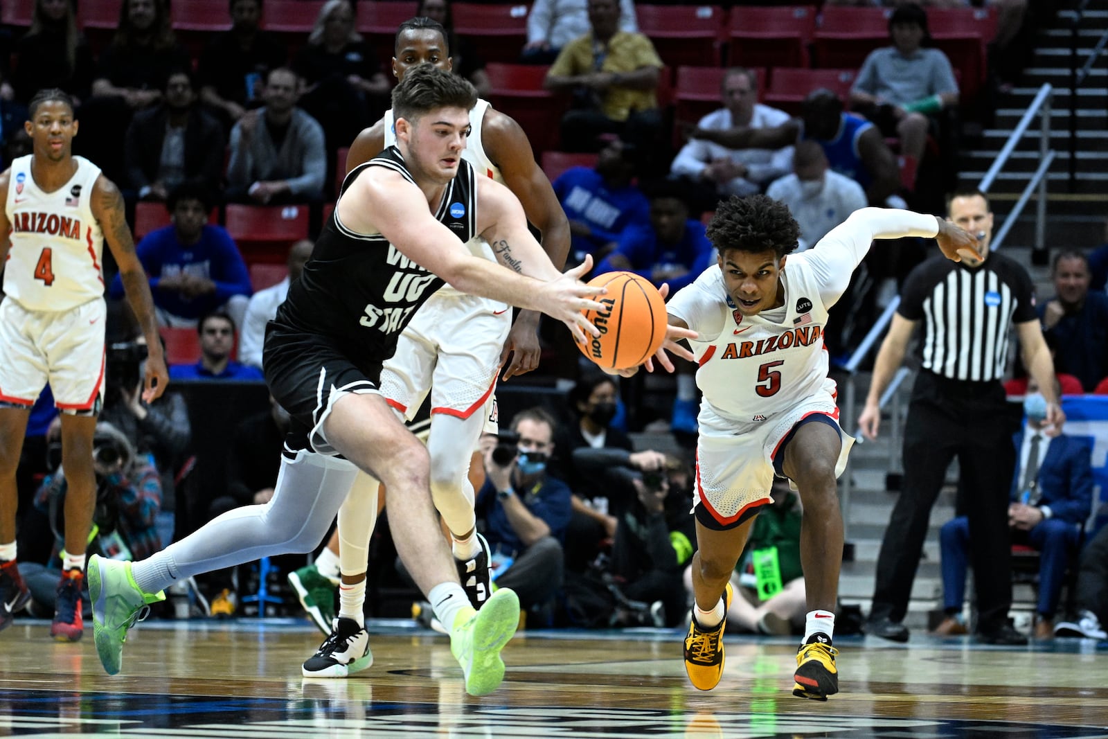 Arizona guard Justin Kier (5) and Wright State forward Grant Basile (00) dive for a loose ball during the second half of a first-round NCAA college basketball tournament game, Friday, March 18, 2022, in San Diego. Arizona won 87-70. (AP Photo/Denis Poroy)