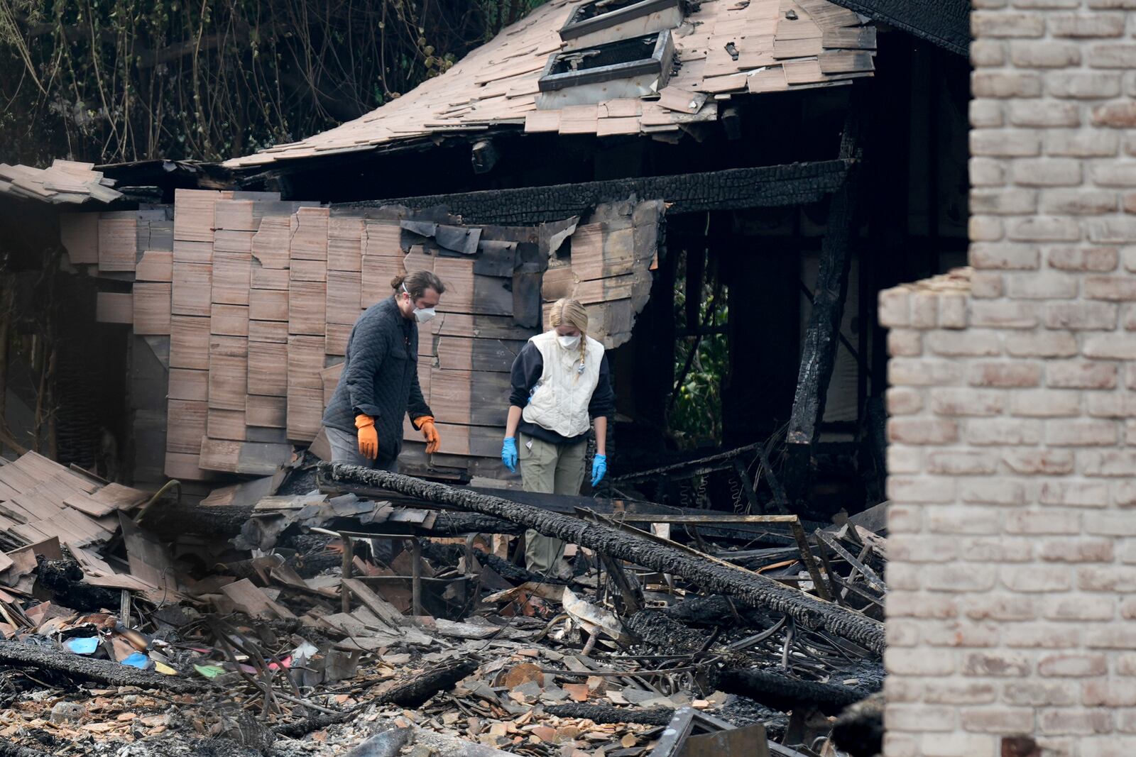 Resident sift through their fire-damage property after the Franklin Fire swept through Wednesday, Dec. 11, 2024, in Malibu, Calif. (AP Photo/Damian Dovarganes)