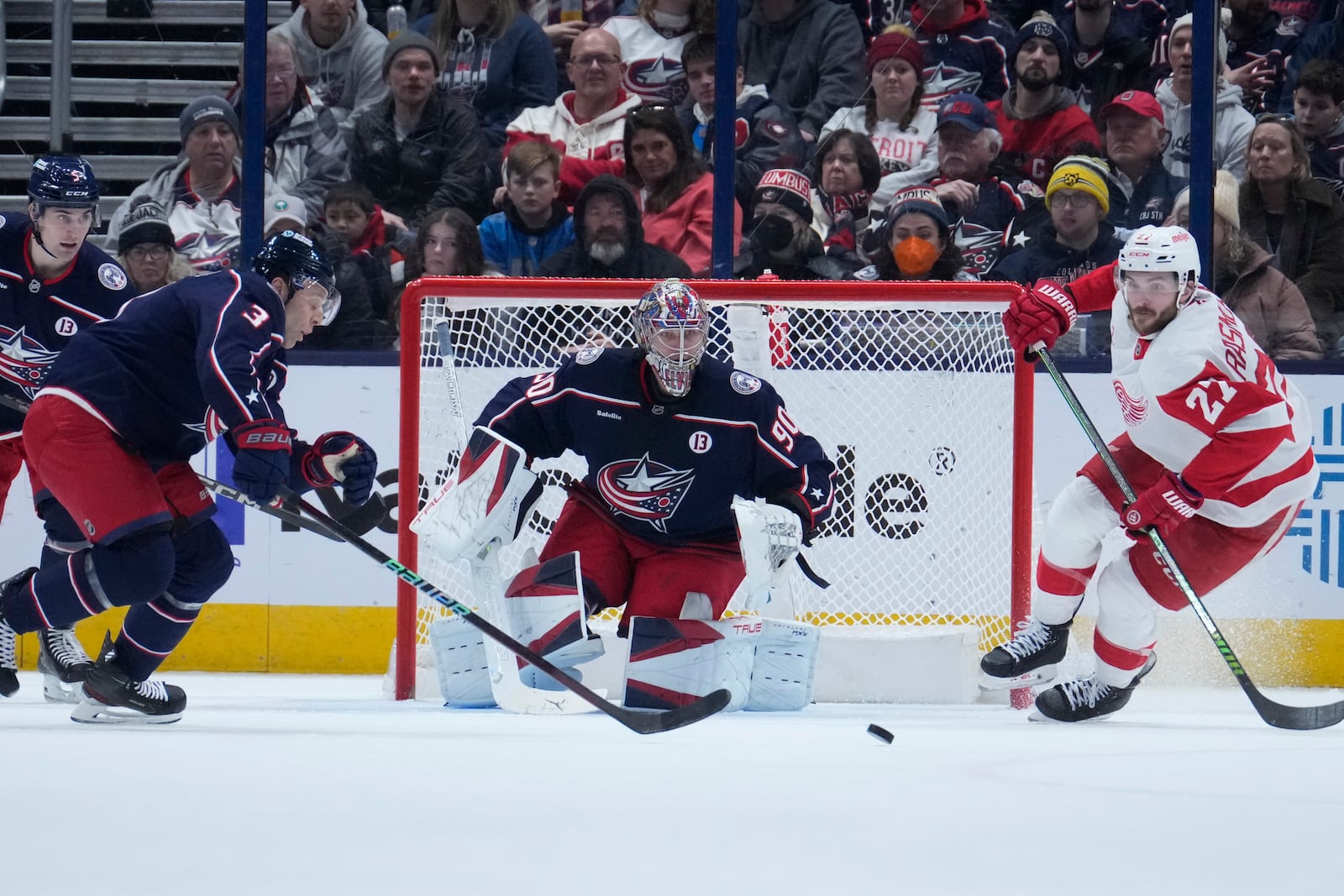 Columbus Blue Jackets defenseman Jack Johnson (3) and Detroit Red Wings center Michael Rasmussen (27) chase the puck in front of goaltender Elvis Merzlikins (90) in the second period of an NHL hockey game in Columbus, Ohio, Thursday, Jan. 2, 2025. (AP Photo/Sue Ogrocki)