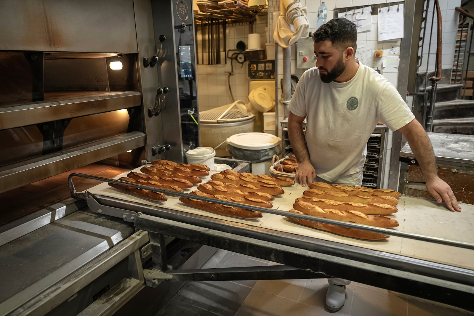 An employee removes bread for the oven in a bakery in Paris, Monday, Dec. 16, 2024 as butter has shot up in price across Europe in recent months, adding more pain to consumers this holiday season after years of inflation in the wake of the COVID-19 pandemic and war in Ukraine.(AP Photo/Aurelien Morissard)