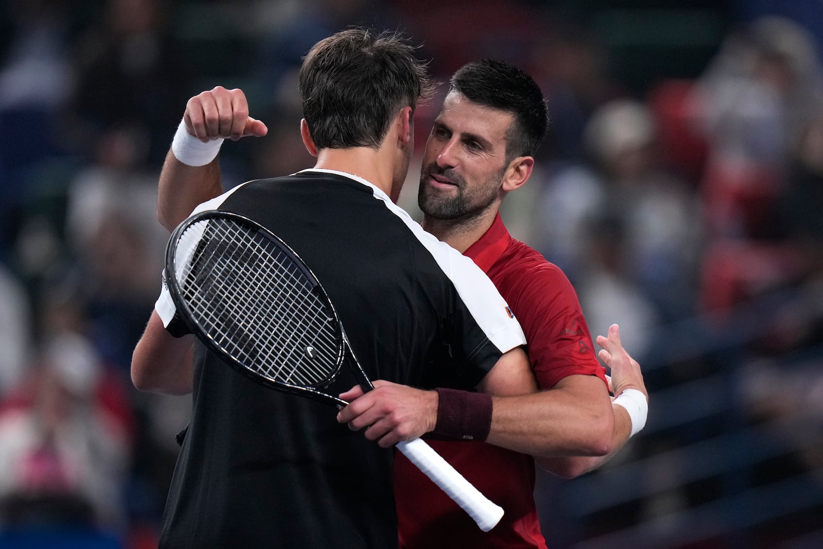 Novak Djokovic of Serbia, right, hugs with Jake Mensik of the Czech Republic after winning in their men's singles quarterfinals match of the Shanghai Masters tennis tournament at Qizhong Forest Sports City Tennis Center in Shanghai, China, Friday, Oct. 11, 2024. (AP Photo/Andy Wong)