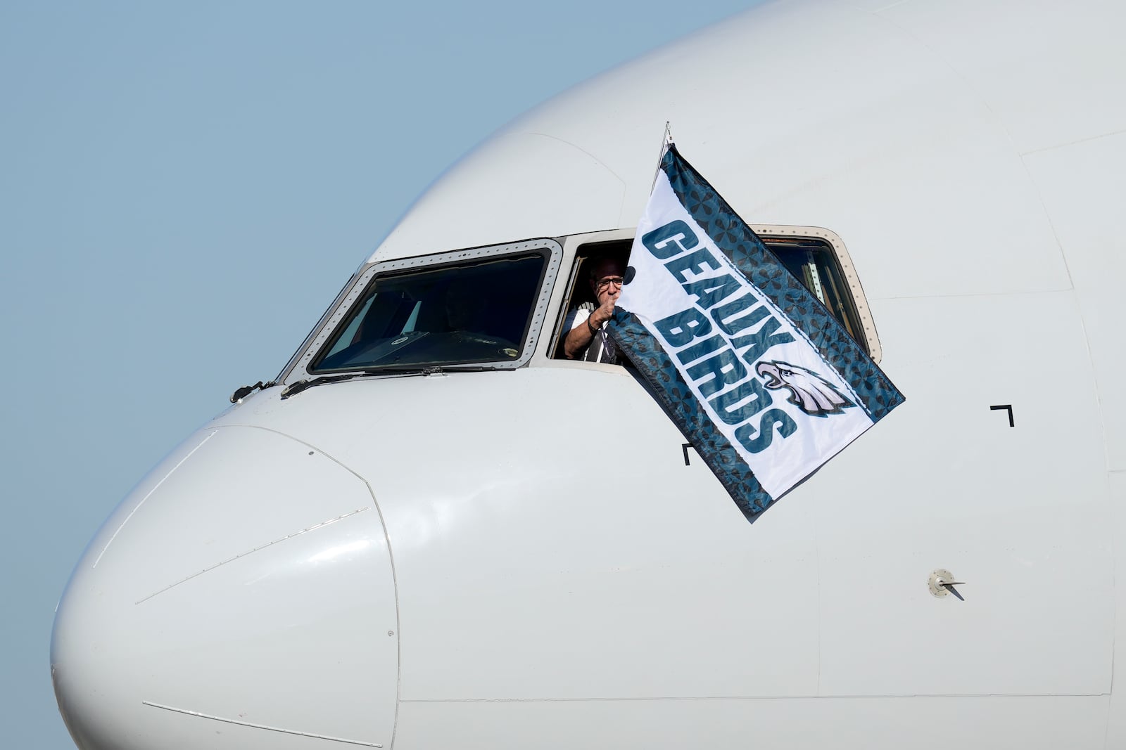 A member of the flight crew waves a Philadelphia Eagles flag after arriving at New Orleans international airport, Sunday, Feb. 2, 2025, in Kenner, La. ahead of the NFL Super Bowl 59 football game between the Philadelphia Eagles and the Kansas City Chiefs. (AP Photo/David J. Phillip)