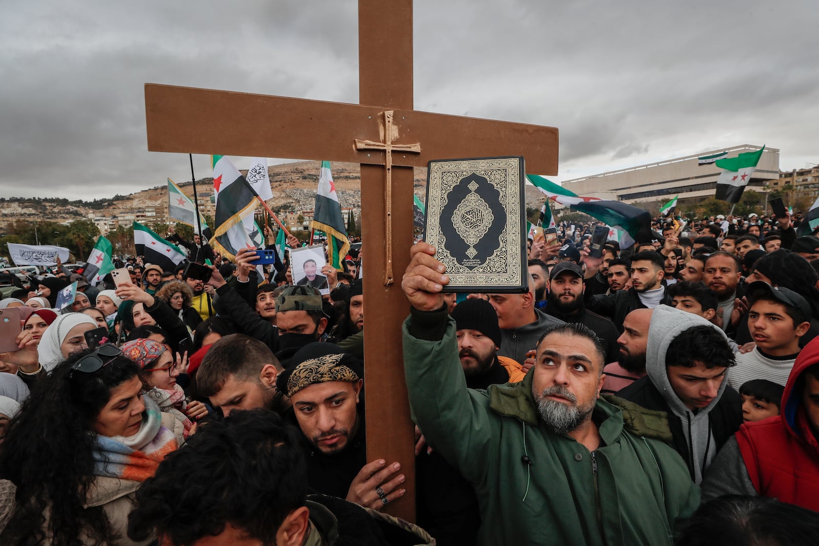 Syrians hold a copy of the Quran next to a Christian cross during a demonstration in support of unity among minorities and the ousting of the Bashar Assad government in Umayyad Square, in Damascus, Syria, Friday, Dec. 27, 2024. (AP Photo/Omar Sanadiki)