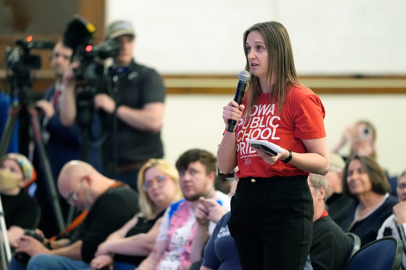 Emma Seibert, a teacher at Des Moines public schools, asks a question for Minnesota Gov. Tim Walz, not pictured, at a town hall event at Roosevelt High School, Friday, March 14, 2025, in Des Moines, Iowa. (AP Photo/Matthew Putney)