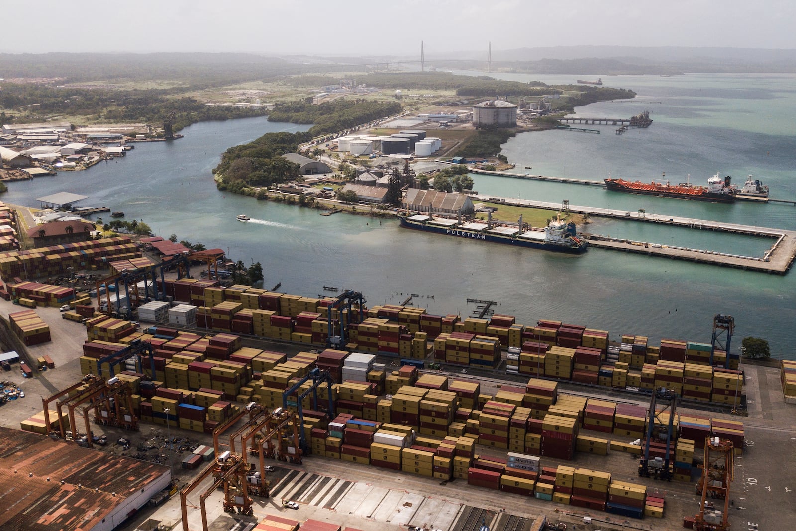 Cargo containers sit stacked as cranes load and unload containers from cargo ships at the Cristobal port, operated by the Panama Ports Company, in Colon, Tuesday, Panama, Feb. 4, 2025. (AP Photo/Matias Delacroix)