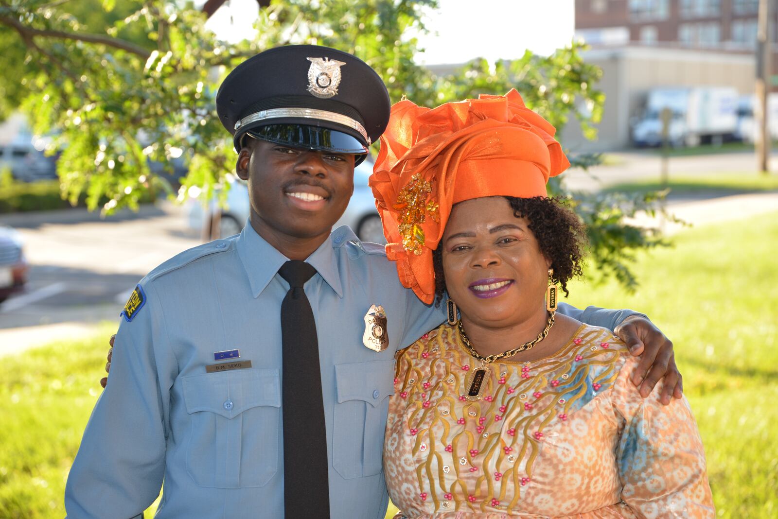 Newly graduated Dayton Police officer Bibebibyo “Bibe” Seko and his mom Sela (orange head wrap) surrounded by their family at Bibe’s graduation. (Photo by Gary Laughlin)